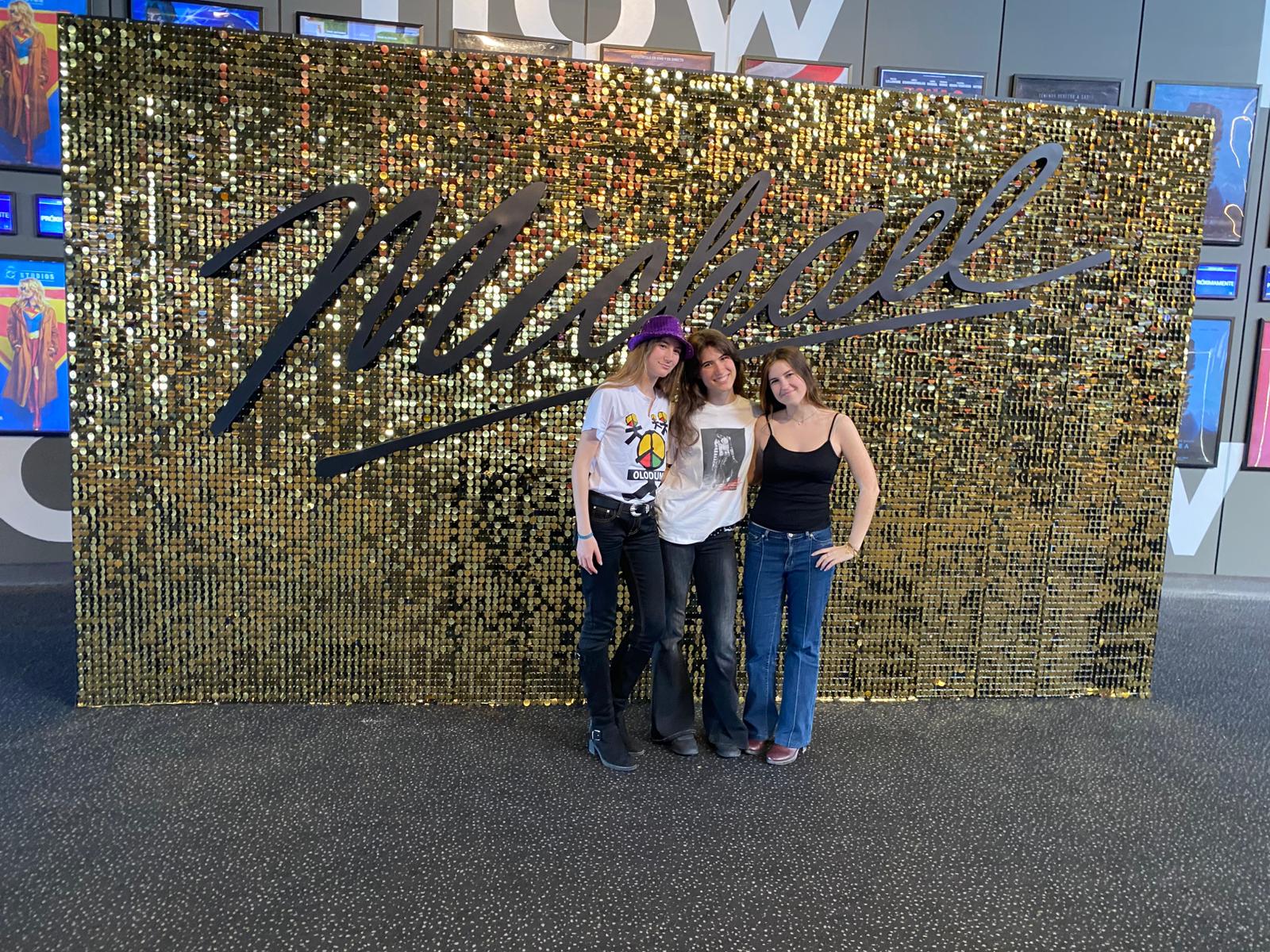 Imagen de tres fanáticas de Michael Jackson y sus canciones posando frente a uno de los carteles de la película